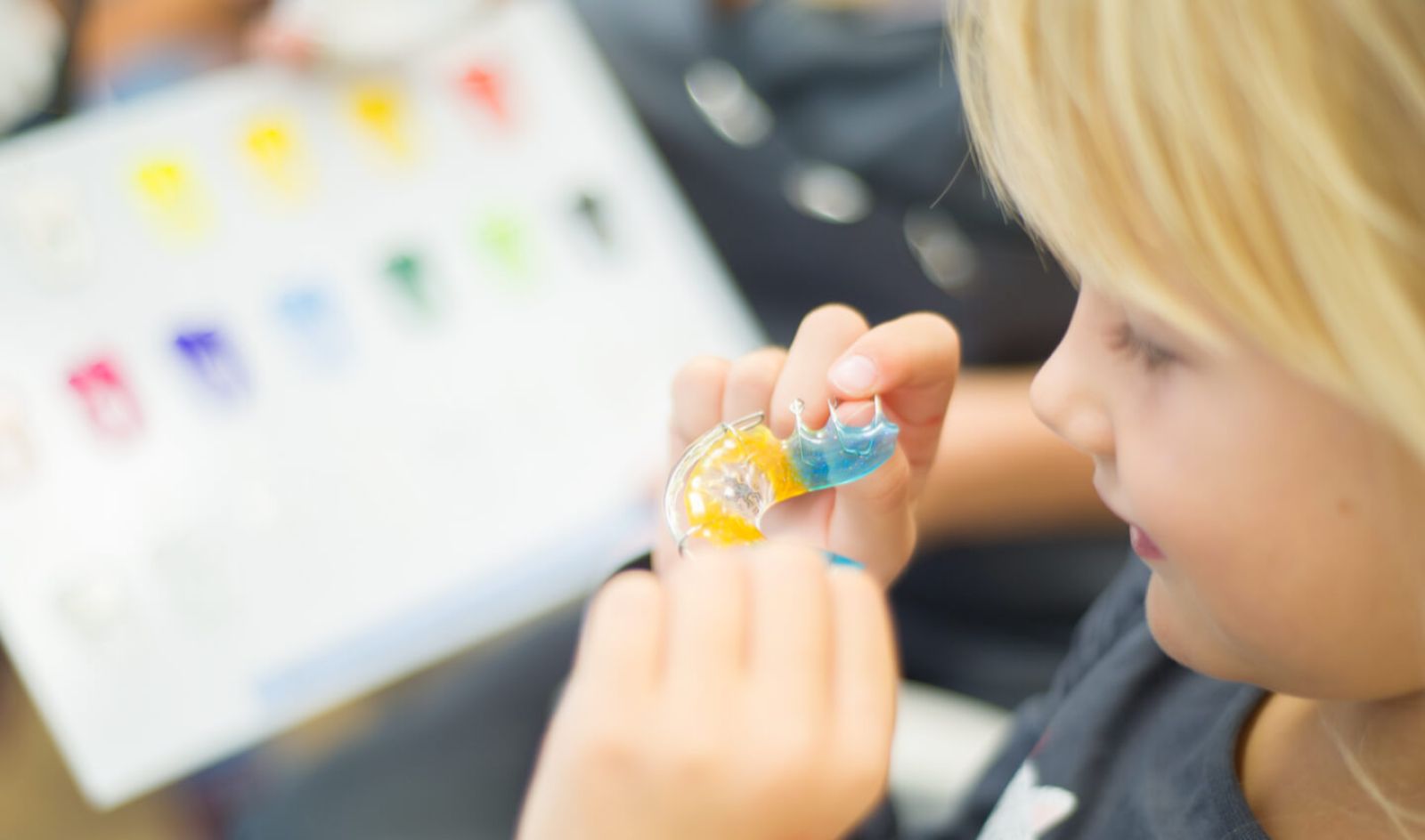 Kleine Patientin schaut sich eine herausnehmbare Zahnspange an. 